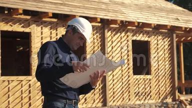概念建筑构建建筑师慢动作视频.. 戴着头盔的建筑工人站在一座建筑上，手持一个